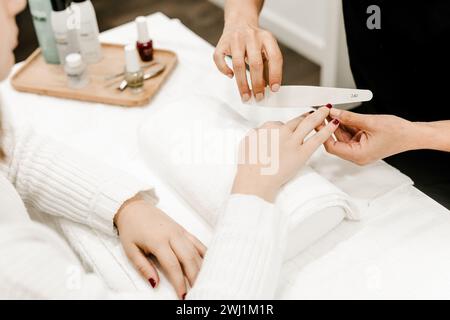 Nahaufnahme einer Maniküre in Bearbeitung mit detaillierter Nagelfeile, Schwerpunkt auf Nagelformung und Nagelpflege. Stockfoto