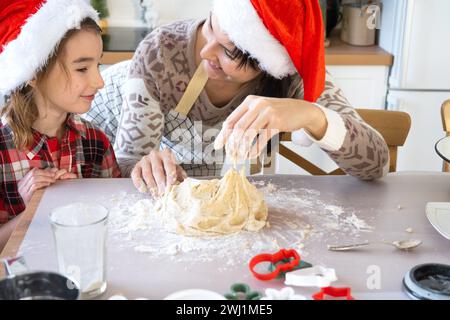 Mom und Tochter in der weißen Küche bereiten Kekse für Weihnachten und Neujahr zu. Familientag, Vorbereitung auf den Urlaub, Stockfoto