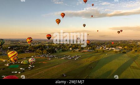 Aus der Vogelperspektive sehen Sie mehrere Heißluftballons, die während eines morgendlichen Starts an einem sonnigen Sommertag aufsteigen Stockfoto