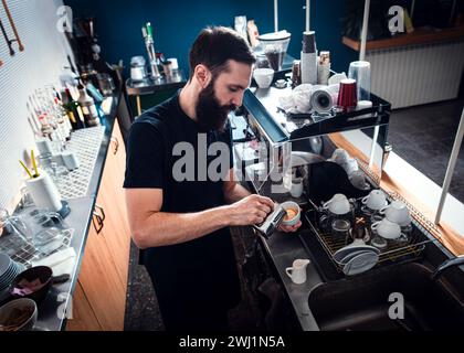 Der Barista bereitet Cappuccino auf einer Espressomaschine für den Gast im Café zu. Stockfoto
