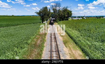 Blick auf die Drohne auf einen Dampfzug, der sich auf einem einzigen Gleis nähert Stockfoto