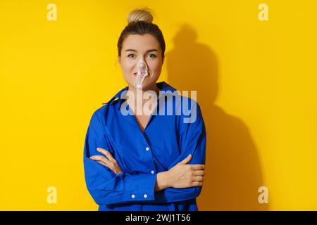 Glückliche Frau, die eine Blase mit Kaugummi vor gelbem Hintergrund bläst Stockfoto