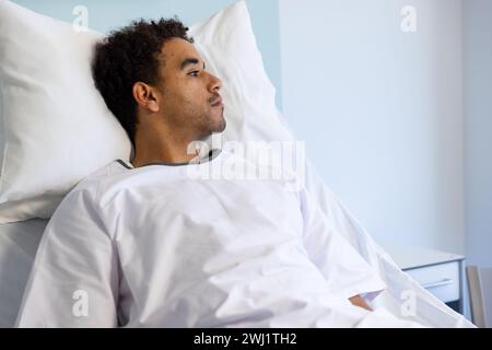 Birassischer männlicher Patient, der im sonnigen Krankenhauszimmer auf Bett liegt Stockfoto