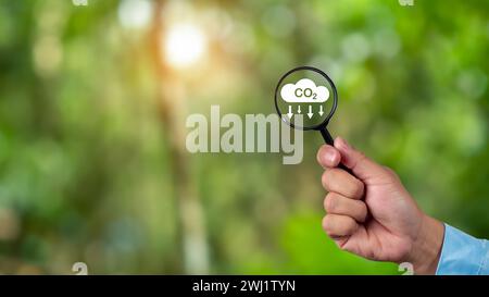 Eine saubere und freundliche Umwelt ohne Kohlendioxidemissionen, Lupe in der Hand mit Symbol zur CO2-Reduktion innen, CO2-Gutschrift an Limi Stockfoto