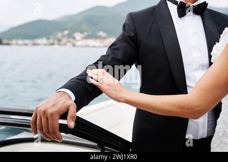 Die Braut berührt die Hand des Bräutigams, während sie in einem Boot steht, das auf dem Meer schwimmt. Abgeschnitten. Gesichtslos Stockfoto