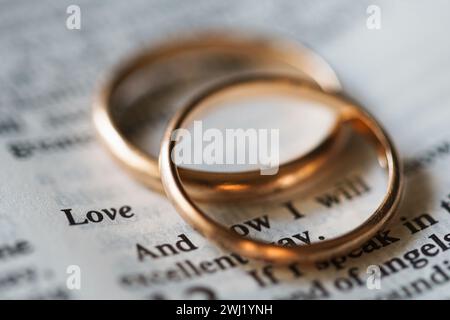 Zwei goldene Eheringe und geöffnete Seiten der heiligen Bibel repräsentieren das Konzept der Ehe und der Liebe zwischen zwei Christen Stockfoto