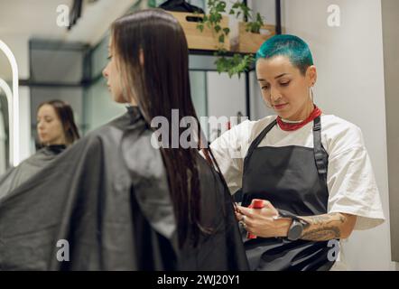 Der Friseur schneidet für weibliche Kunden Haare mit einer Schere, um Haare in einem Schönheitssalon zu schneiden Stockfoto