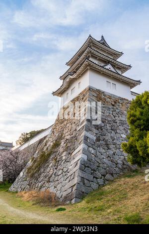 Schloss Akashi. Die sehr hohen ishigaki-Steinmauern stützen den Tatsumi Yagura, Turm, der sich über einem blauen Himmel mit flauschigen weißen Wolken erhebt. Stockfoto