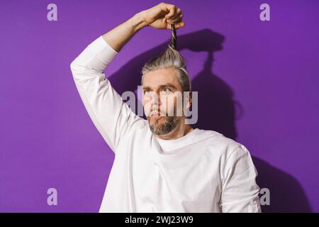 Dummer Mann mittleren Alters, der vor purpurrotem Hintergrund herumtäuscht Stockfoto