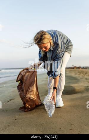 Glückliche Freiwillige sammelt Plastikmüll am Strand, um die Natur sauber zu halten Stockfoto