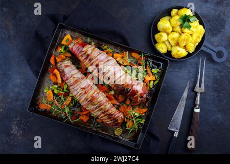 Gebratenes Mangalica-Schweinefilet, gefüllt mit gehackten Walnüssen und Kürbis, in Speck gewickelt, serviert mit Gemüse und gekocht Stockfoto