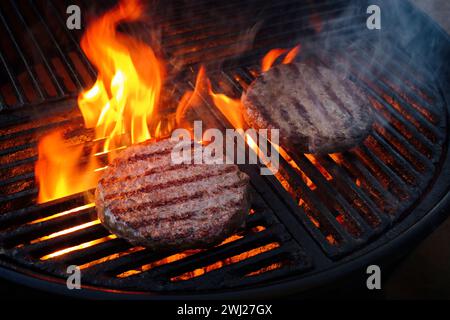 Barbecue Wagyu Beef Hamburger gegrillt aus nächster Nähe auf einem Holzkohlegrill mit Feuer und Rauch Stockfoto