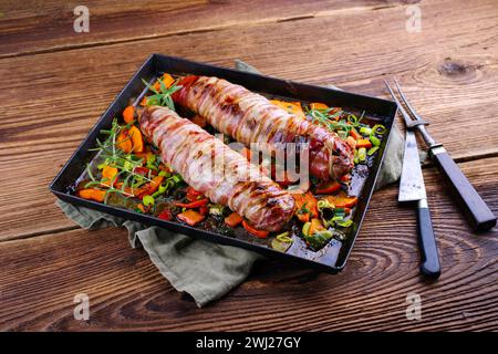 Geröstetes Mangalica-Schweinefilet gefüllt mit gehackten Walnüssen und Kürbis und in Speck gewickelt, serviert mit Gemüse als Clos Stockfoto