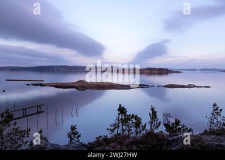 Erhöhter Blick auf den Morgenhimmel mit magentafarbenen Wolken über die felsige Küstenlandschaft in Schweden Stockfoto