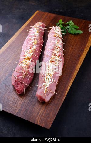 Rohes Mangalica-Schweinefilet gefüllt mit gehackten Walnüssen und Kürbis als Nahaufnahme auf einem hölzernen Schneidebrett Stockfoto