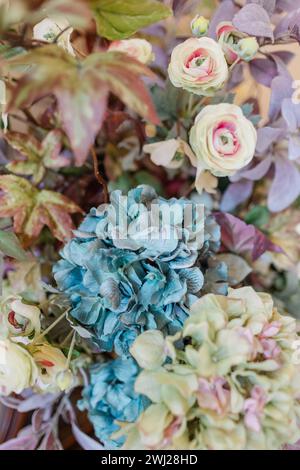 Kunstblumen-Arrangement mit Hortensien und Rosen in gedeckten Farben Stockfoto