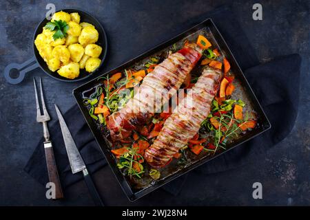 Gebratenes Mangalica-Schweinefilet, gefüllt mit gehackten Walnüssen und Kürbis, in Speck gewickelt, serviert mit Gemüse und gekocht Stockfoto