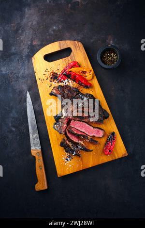 Traditionelles, trocken gereiftes angus-Rindersteak mit gegrilltem Paprika serviert als Blick von oben auf einem hölzernen Design-Brett Stockfoto