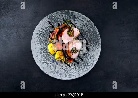 Gebratenes Mangalica-Schweinefilet, gefüllt mit gehackten Walnüssen und Kürbis, in Speck gewickelt, serviert mit Gemüse und gekocht Stockfoto