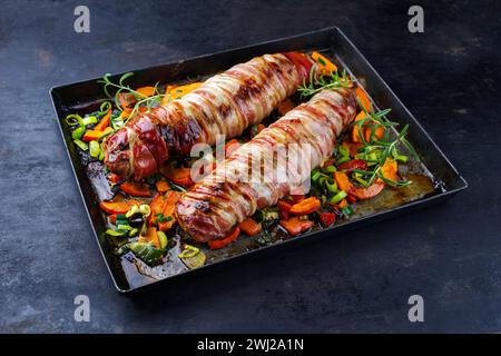 Geröstetes Mangalica-Schweinefilet gefüllt mit gehackten Walnüssen und Kürbis und in Speck gewickelt, serviert mit Gemüse als Clos Stockfoto