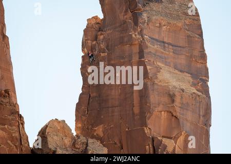 Entschlossener Bergsteiger, der felsige Klippen in der Wüste klettert Stockfoto