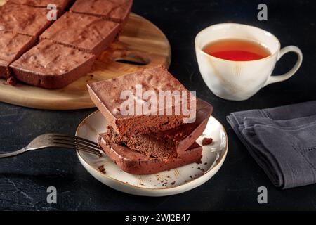 Schokoladenbrownie mit Tee, einfacher Kaffeekuchen, auf schwarzem Schiefergrund Stockfoto