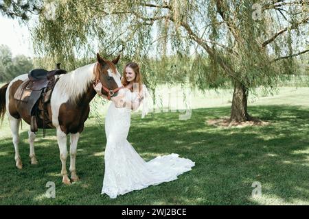 Braut im Hochzeitskleid, die ihr Pferd hält Stockfoto