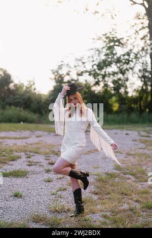 Cowgirl steht auf dem Feld, hüpfend, mit Fransenkleid Stockfoto