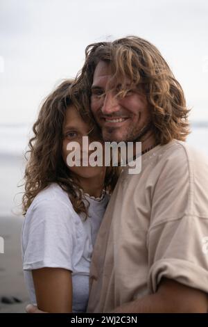 Ein junges, fröhliches, verliebtes Paar, das am Strand spaziert. Stockfoto
