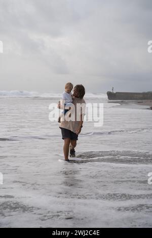 Vater, der am Strand das Kindlein aufrakelt Stockfoto