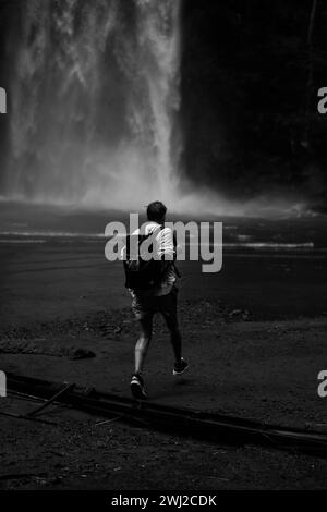 Reisende, Entdeckerin mit Rucksack im Dschungel, am Wasserfall. Stockfoto