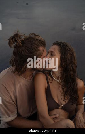 Junges fröhliches, verliebtes Paar, das sich am Strand küsst. Stockfoto