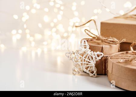 Nachhaltige Weihnachtsgeschenkboxen mit natürlichem Dekor auf glänzendem Bokeh-Hintergrund. Weihnachten Zero Waste, Boxtag und Winterurlaub Stockfoto