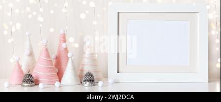Banner mit selbstgebauten Weihnachtsbäumen aus rosa Garn und weißem Rahmen auf dem Tisch. Modell Vorderansicht. Öko flauschige Weihnachtsdekoration Stockfoto