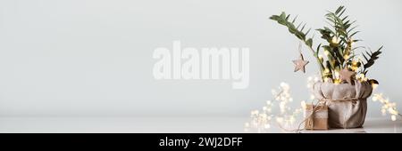 Banner mit Weihnachtsbaum aus Zimmerpflanze. Geschenkboxen in Papier, mit Spitze und Garn verziert. Öko-weihnachtliche Einrichtung Stockfoto