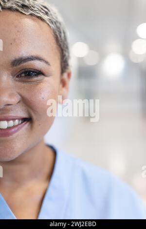 Porträt einer glücklichen birassischen Ärztin mit kurzen Haaren, die Peelings im Spitalflur trägt Stockfoto