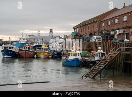 Kommerzielle Boote liegen im Hafen von Scarborough mit dem Fischmarkt hinter dem Kai in Yorkshire, England Stockfoto