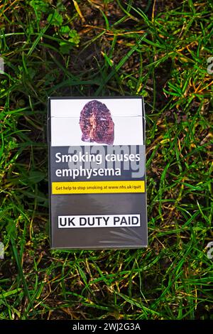 Eine weggeworfene Zigarettenpackung auf Grashintergrund mit erkrankter Lunge, verursacht durch Rauchen, zeigt Emphysema-Warnung in Großbritannien KATHY DEWITT Stockfoto