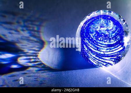 Eine transparente Glaskugel mit Einschlüssen wirft echte Schatten auf einem weißen Hintergrund Stockfoto