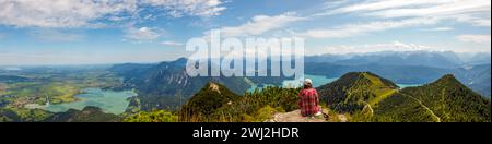 Frau, die nach dem Wandern auf dem Berg Herzogstand sitzt und sich entspannt. Sehen Sie sich das spektakuläre an Stockfoto