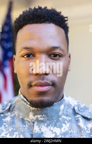 Fokussierter afroamerikanischer männlicher Soldat vor dem Haus mit usa-Flagge, Kopierraum Stockfoto