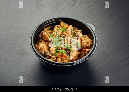 Traditionelles asiatisches Gericht, Huhn oder Schwein mit Reis und Pilzen in einer Plastikschale Stockfoto