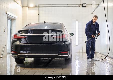 Gutaussehender, engagierter professioneller Mitarbeiter mit gesammeltem Haarwaschwagen, während er in der Garage ist Stockfoto