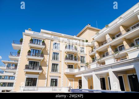 Gelbe Fassade des Regent Hotels mit Terrassen vor dem blauen Himmel. Porto, Montenegro Stockfoto