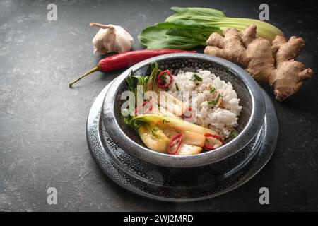 Vegetarische Mahlzeit aus Reis ad Pak Choi (Chinakohl) mit Ingwer, Knoblauch und rotem Chili in einer schwarzen Keramikschale auf A da Stockfoto