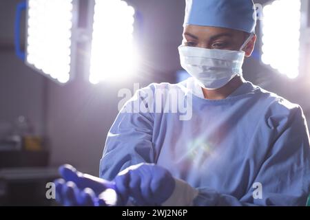 Birassische Chirurgin mit Operationsmantel und medizinischen Handschuhen im Operationssaal Stockfoto