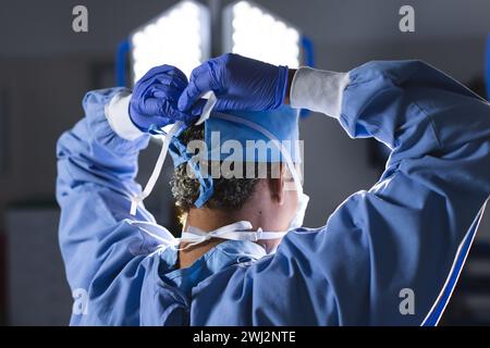 Birassische Chirurgin mit Operationsmantel und Gesichtsmaske im Operationssaal Stockfoto