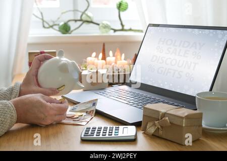 Frauenhände schütteln Münzen aus einer Sparkasse, während sie online Weihnachtsgeschenke kaufen, um die Weihnachtsgeschenke zu nutzen Stockfoto