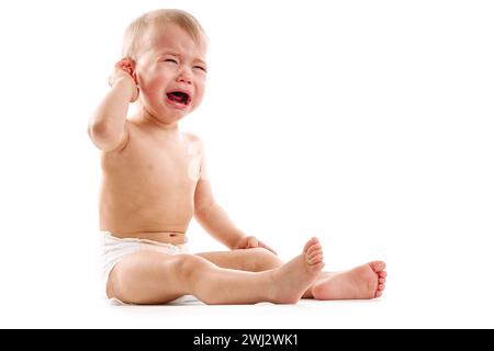 Verärgerter kleiner Junge in Windel sitzt und weint. Stockfoto