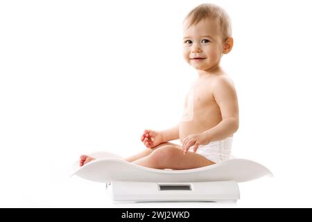 Wiegen eines kleinen Jungen in Windel, der auf Waage sitzt. Stockfoto